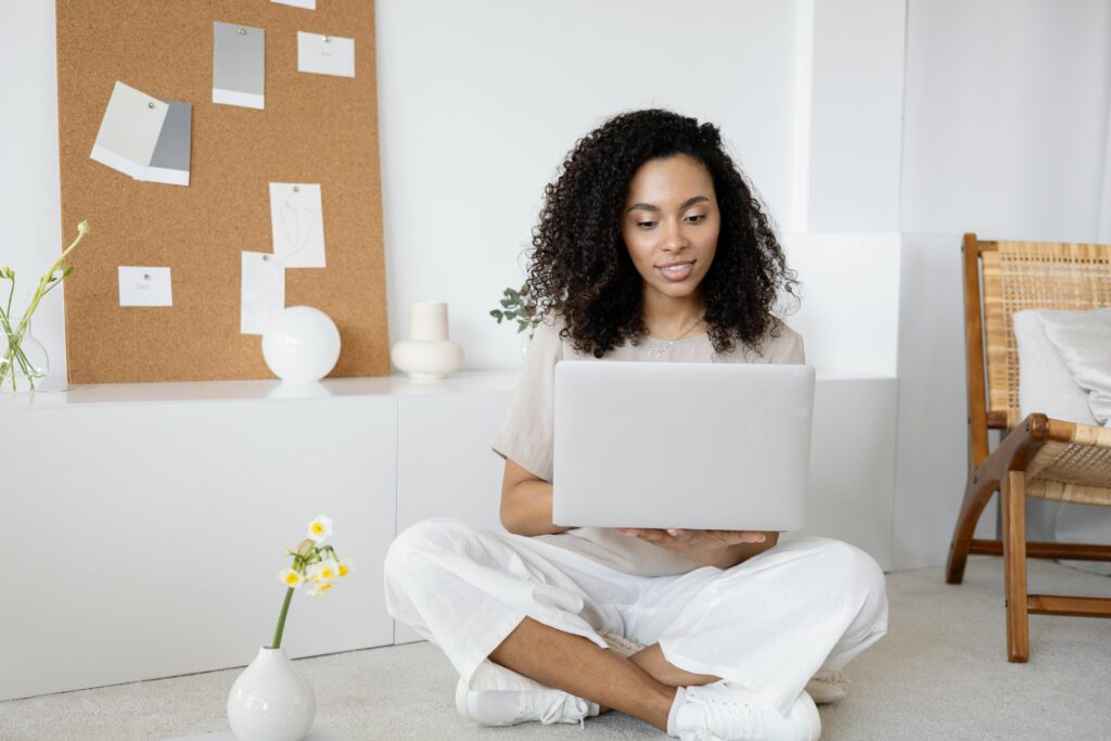 pexels-photo-7552374-7552374 Young woman with curly hair working on her laptop in a cozy home setting, exuding confidence and focus.
