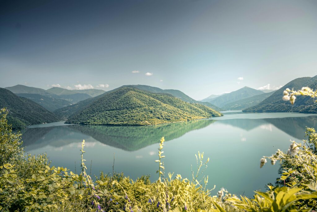 pexels-photo-2804123-2804123 Tranquil lake surrounded by lush green mountains under a clear summer sky.