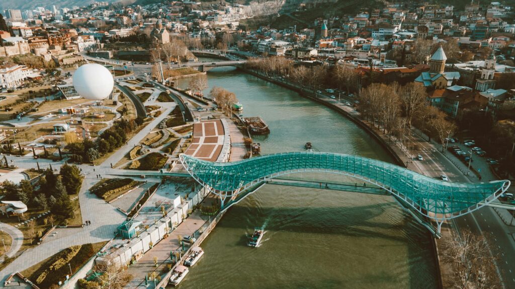 pexels-photo-7539816-7539816 Aerial view of Peace Bridge over Kura River in Tbilisi, Georgia, showcasing urban landscape.